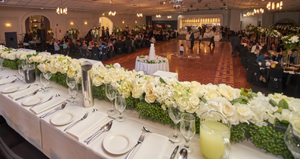 Beautiful table setting for a wedding including white roses the whole length of long white tables
